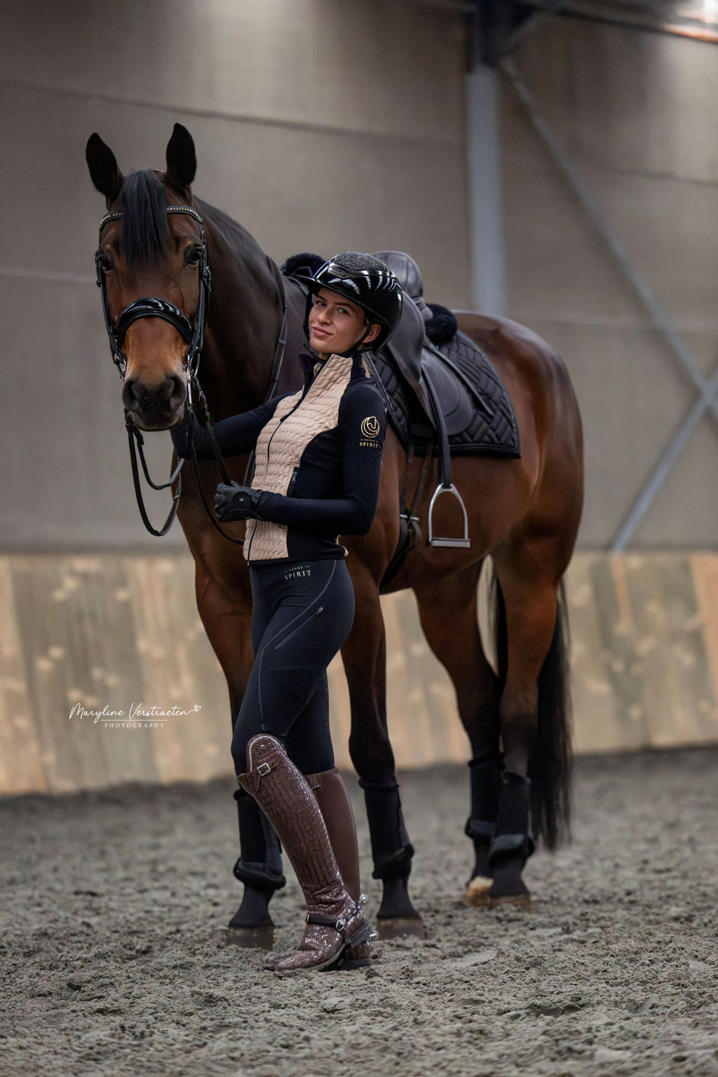 Side view of model with horse, highlighting the contrast between the jacket's insulated back panel and breathable side panels while grooming or tacking up.