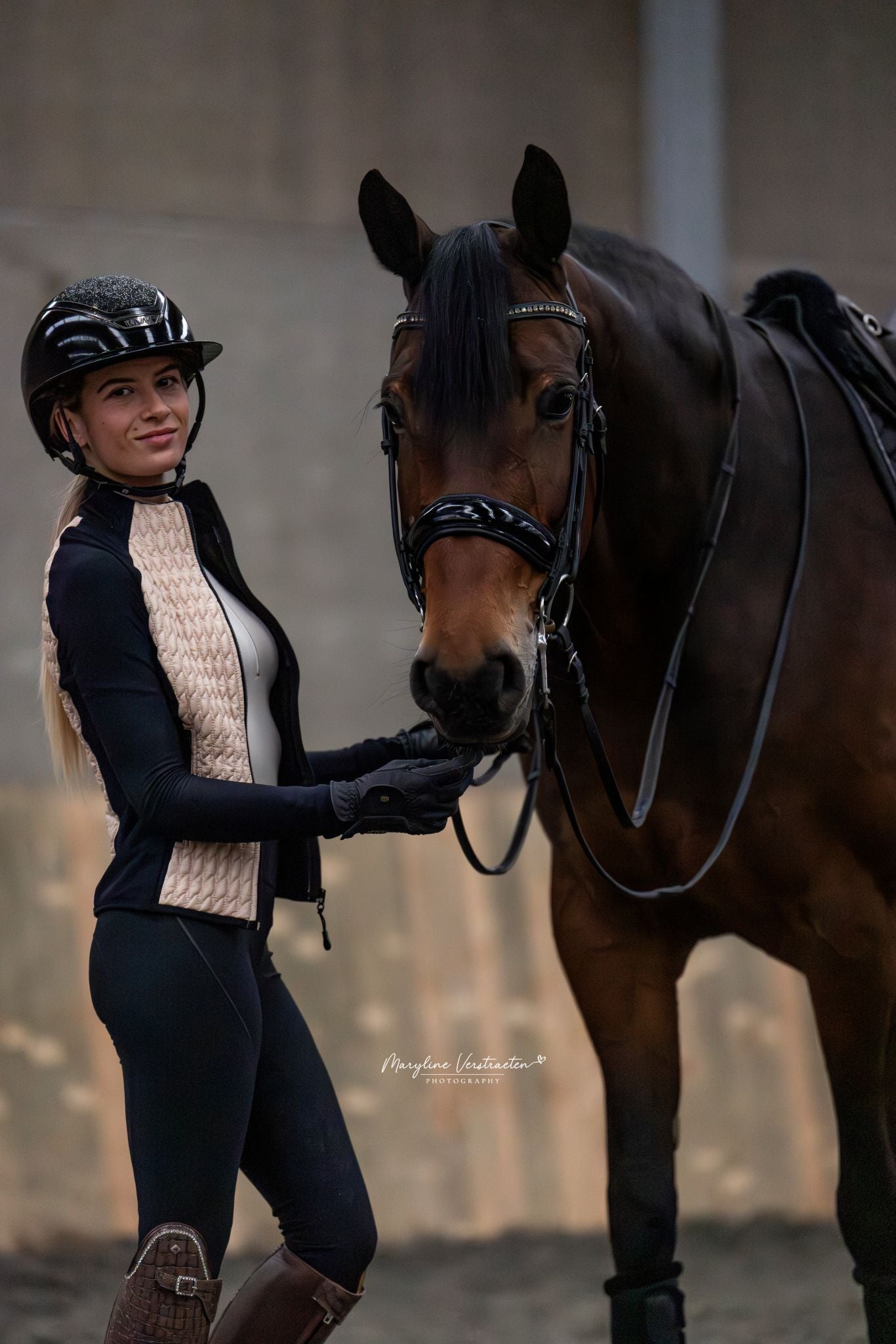 Side view of model with horse, highlighting the contrast between the jacket's insulated back panel and breathable side panels while grooming or tacking up.