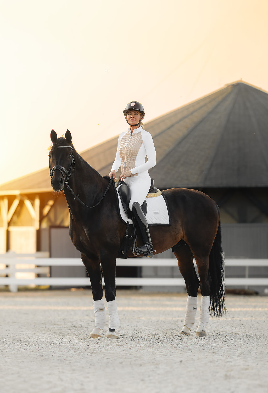Show ring ready – female competitor in Horse Spirit white hybrid jacket on horseback, combining elegance with advanced breathability and warmth.