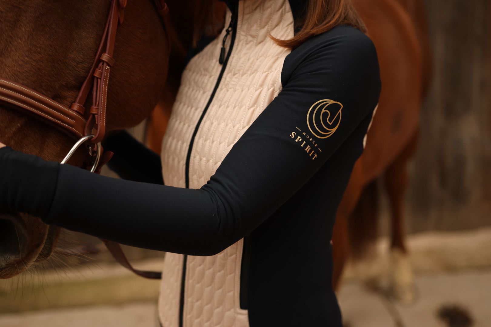 Close-up detail of the Horse Spirit Hybrid Jacket - Quilted beige insulation panel, breathable black side fabric with the Horse Spirit logo..